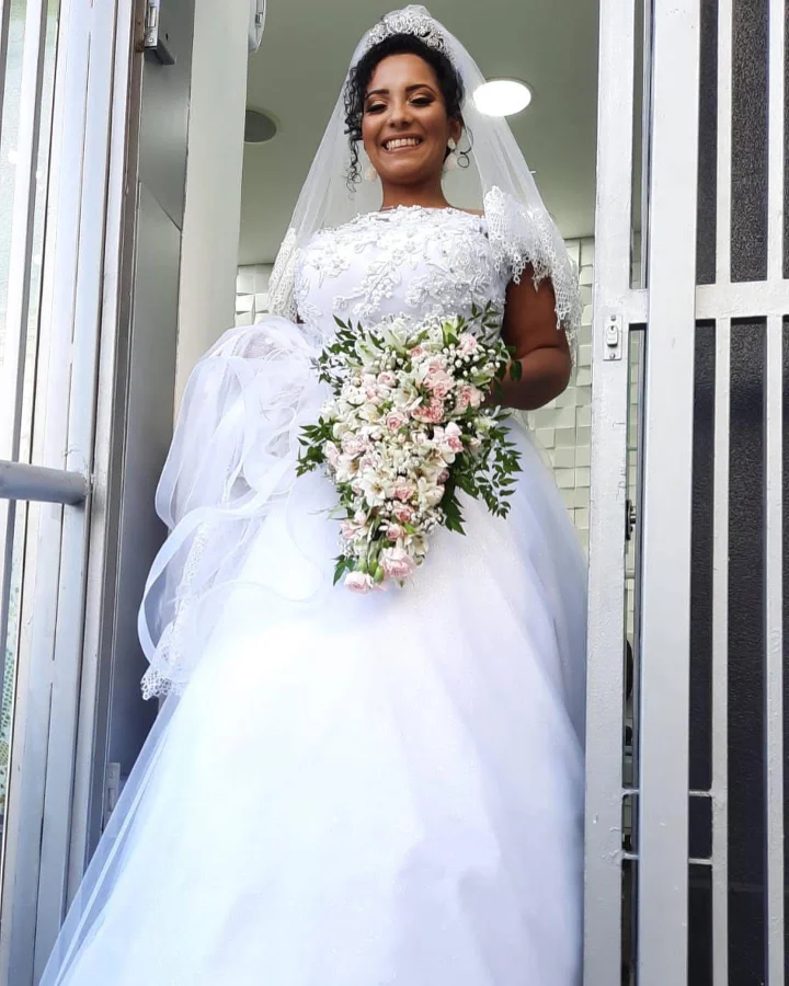 Noiva sorridente segurando buquê de flores na porta do salão