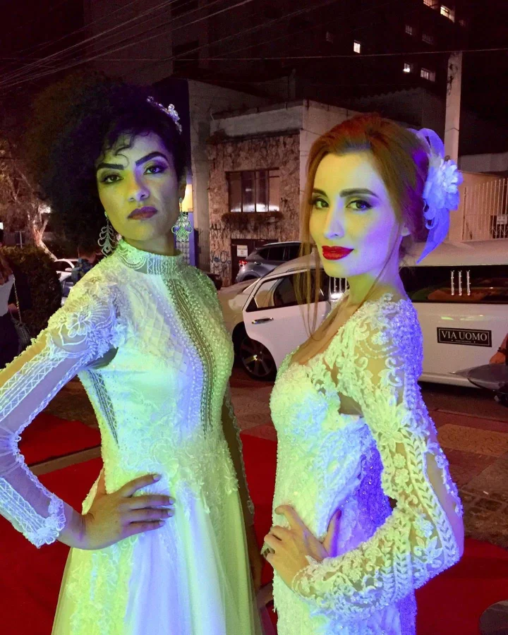 Duas noivas posando lado a lado durante a noite