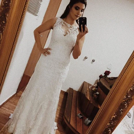 Noiva com vestido rendado justo em frente ao espelho