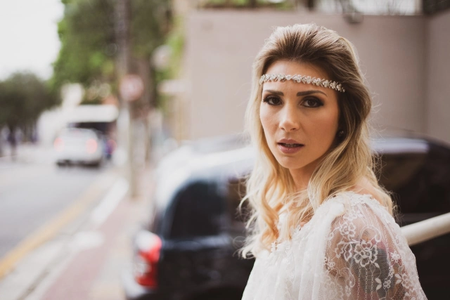 Noiva com tiara de pérolas na rua, ao lado de um carro